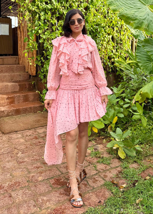 Woman in a pink dress standing outdoors with greenery around
