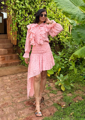 Woman in a pink dress standing in a garden with greenery around.